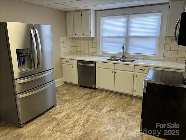 kitchen with sink, tile counters, black appliances, and white cabinets