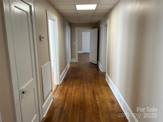 hall featuring a drop ceiling and dark hardwood / wood-style flooring