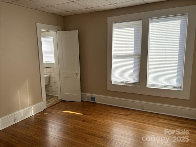 spare room with hardwood / wood-style floors and a paneled ceiling