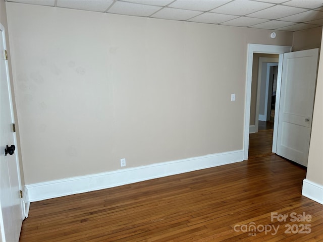 unfurnished room featuring dark wood-type flooring and a drop ceiling