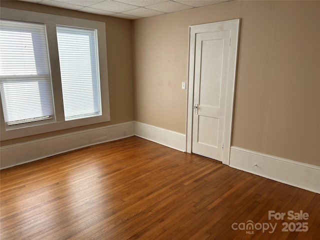 empty room featuring hardwood / wood-style flooring and a drop ceiling