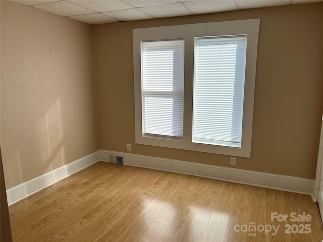 empty room with a paneled ceiling and light hardwood / wood-style floors