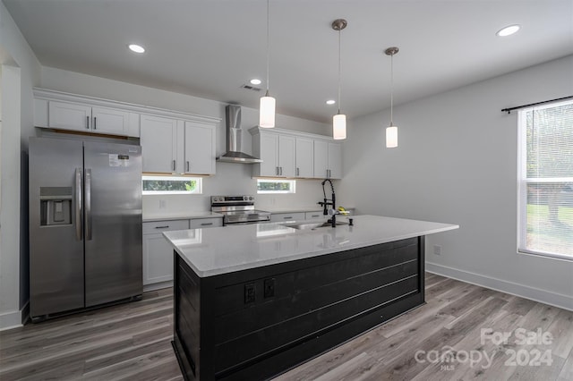 kitchen with stainless steel appliances, sink, wall chimney range hood, hardwood / wood-style flooring, and white cabinetry