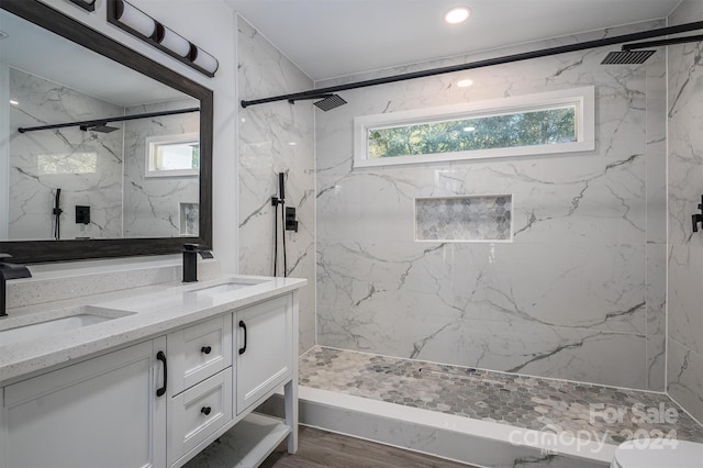 bathroom with tiled shower, hardwood / wood-style floors, and vanity