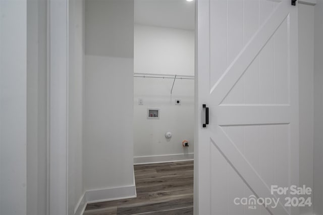 clothes washing area featuring hookup for a gas dryer, hookup for a washing machine, dark hardwood / wood-style floors, a barn door, and hookup for an electric dryer