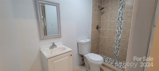 bathroom with a tile shower, vanity, and toilet