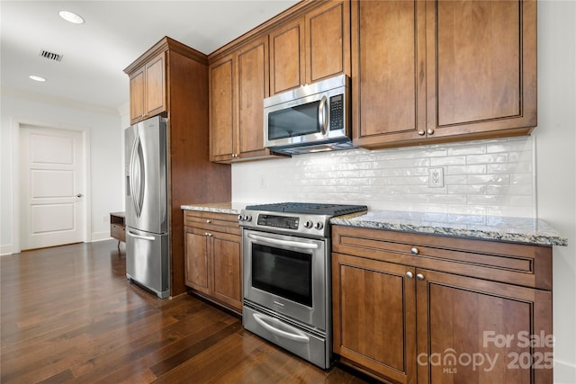 kitchen with backsplash, stainless steel appliances, light stone counters, and dark hardwood / wood-style floors