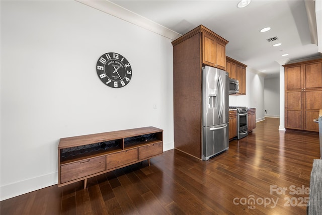 kitchen with dark hardwood / wood-style flooring, stainless steel appliances, and ornamental molding