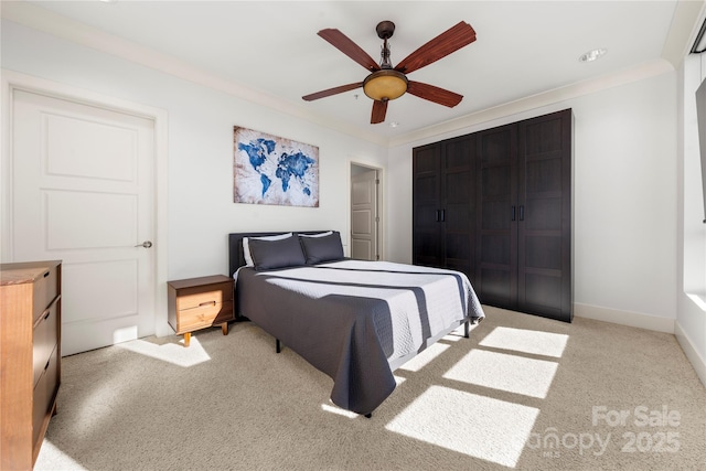 carpeted bedroom featuring ceiling fan, ornamental molding, and a closet