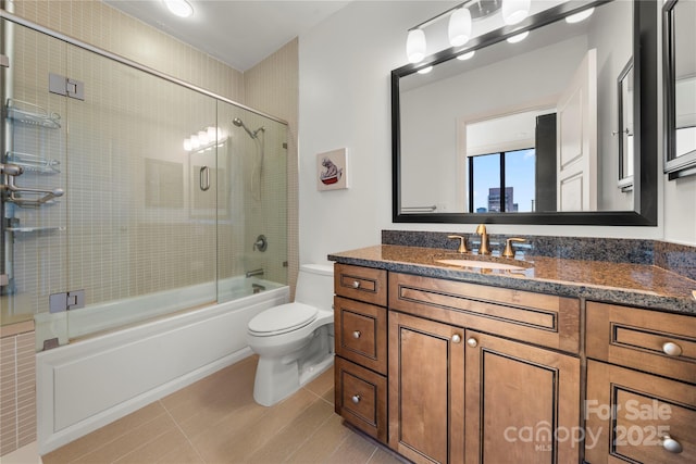 full bathroom featuring toilet, vanity, tile patterned floors, and bath / shower combo with glass door