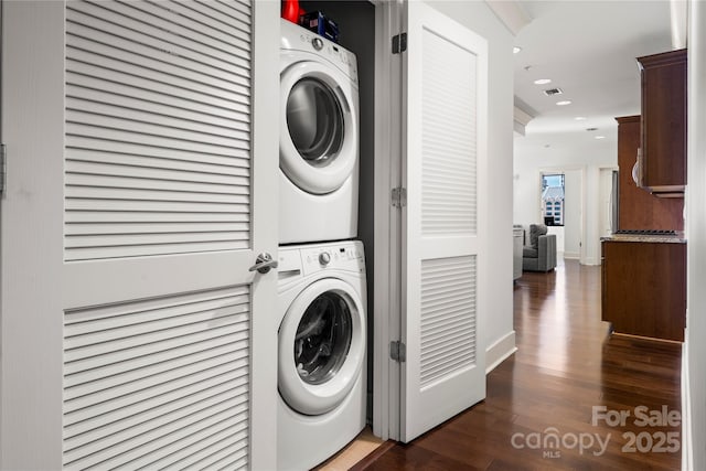 washroom featuring dark hardwood / wood-style flooring and stacked washer / dryer