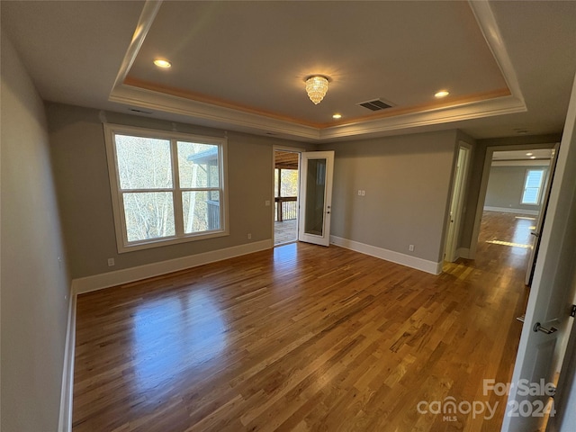 spare room with dark wood-type flooring and a tray ceiling