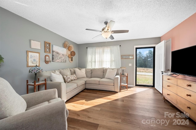 living room featuring ceiling fan, light hardwood / wood-style floors, and a textured ceiling