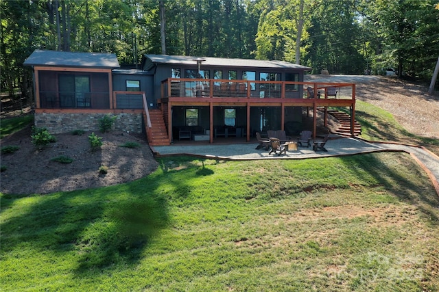 rear view of house with a sunroom, a deck, a patio, and a yard