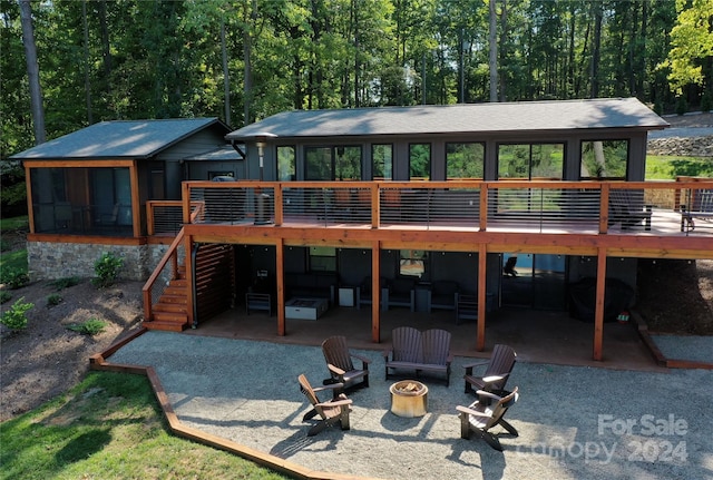 back of property with a fire pit, a patio area, and a wooden deck