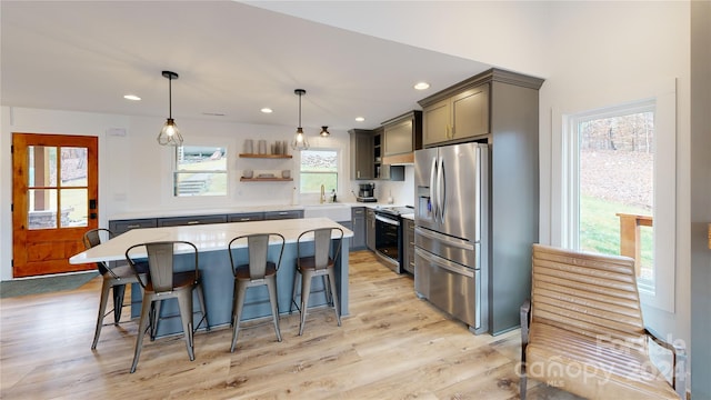 kitchen with a healthy amount of sunlight, hanging light fixtures, appliances with stainless steel finishes, and light hardwood / wood-style flooring