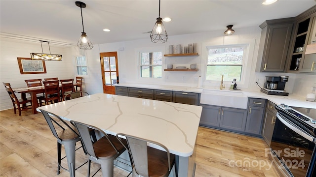 kitchen featuring light stone countertops, a wealth of natural light, sink, and pendant lighting