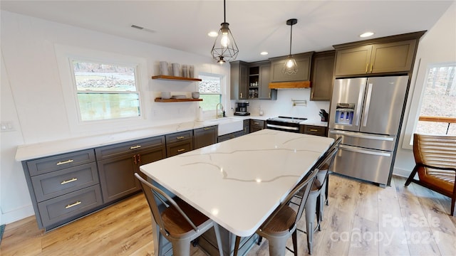 kitchen featuring a center island, stainless steel fridge, light wood-type flooring, and pendant lighting