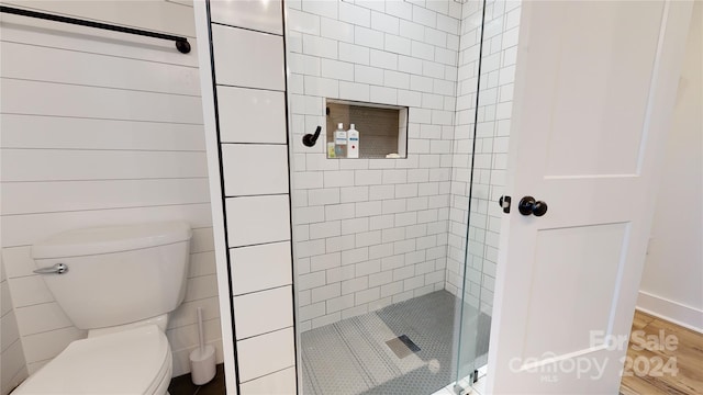 bathroom featuring hardwood / wood-style floors, toilet, and tiled shower