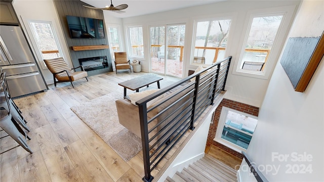 living room with a fireplace, ceiling fan, and light hardwood / wood-style flooring