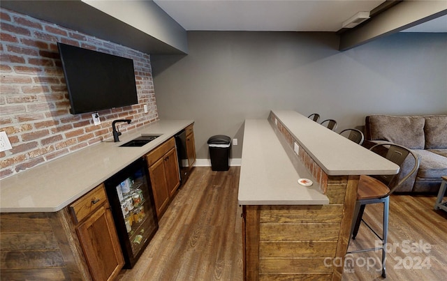 bar with dishwasher, light hardwood / wood-style flooring, beverage cooler, and sink