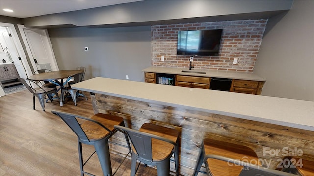 bar featuring black dishwasher, light hardwood / wood-style flooring, and sink