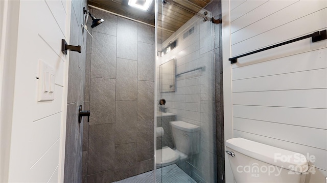 bathroom with toilet, a shower with door, and wooden walls