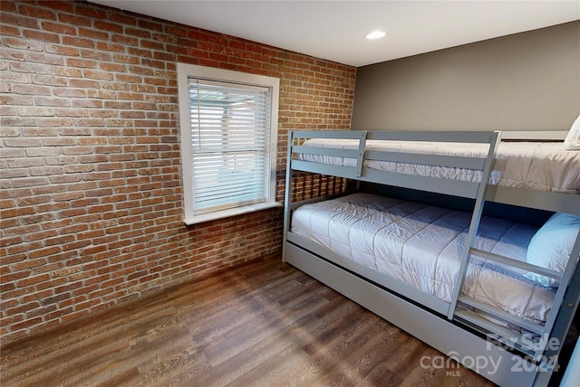 bedroom featuring hardwood / wood-style floors and brick wall