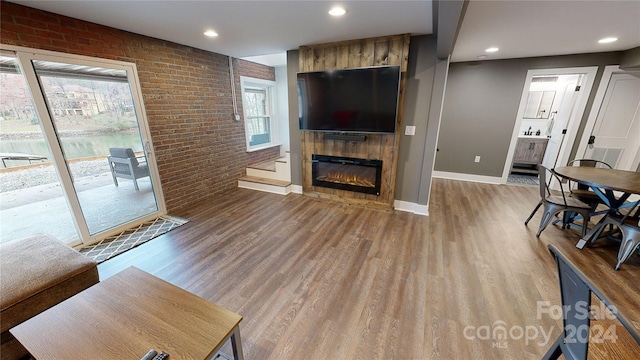 living room featuring a fireplace, wood-type flooring, and brick wall