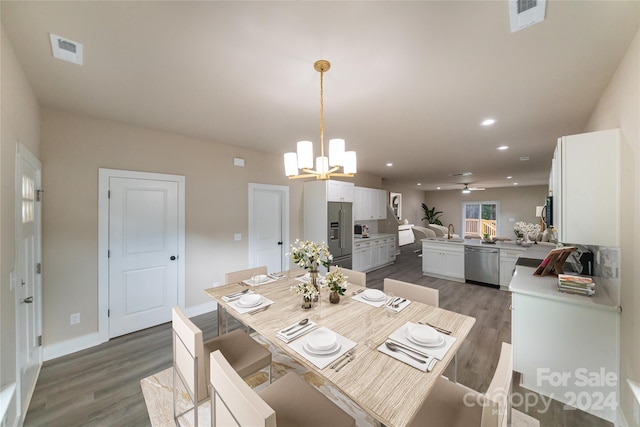 dining space featuring sink, dark wood-type flooring, and ceiling fan with notable chandelier