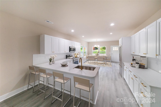 kitchen featuring sink, kitchen peninsula, a breakfast bar, white cabinets, and appliances with stainless steel finishes