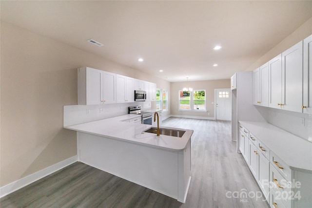 kitchen with kitchen peninsula, appliances with stainless steel finishes, white cabinets, and sink