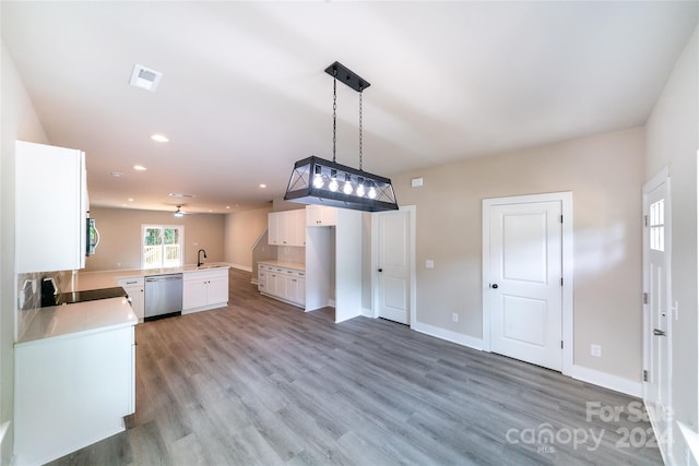 kitchen with white cabinets, kitchen peninsula, stainless steel dishwasher, and hardwood / wood-style flooring