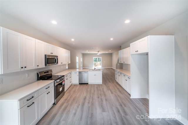 kitchen featuring light hardwood / wood-style floors, white cabinetry, kitchen peninsula, and appliances with stainless steel finishes