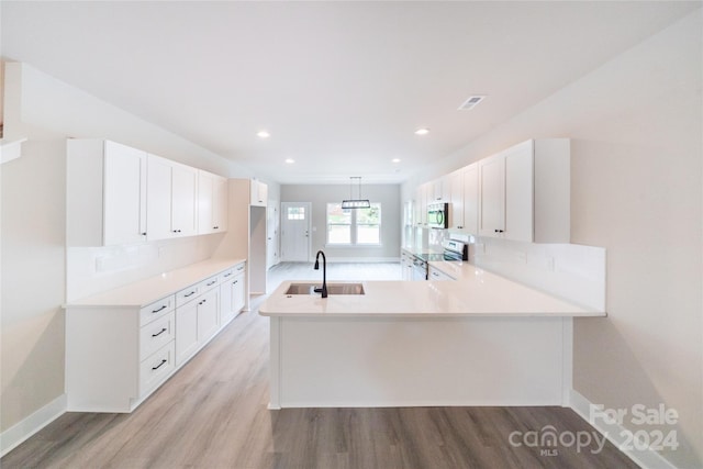 kitchen with kitchen peninsula, appliances with stainless steel finishes, white cabinets, and sink