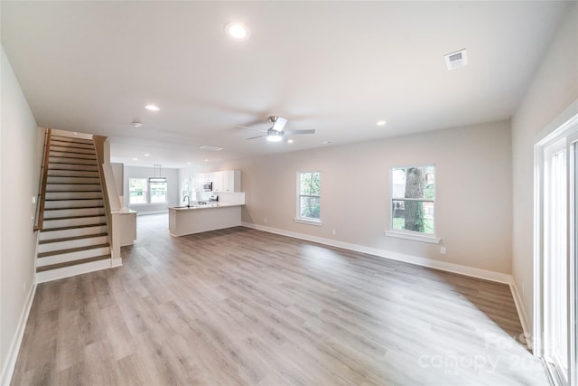 unfurnished living room with light hardwood / wood-style floors, ceiling fan, and sink