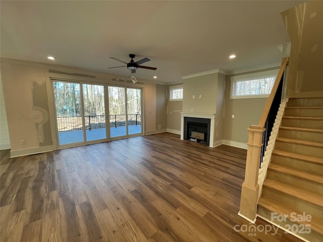 unfurnished living room with baseboards, dark wood-style floors, stairs, crown molding, and a fireplace