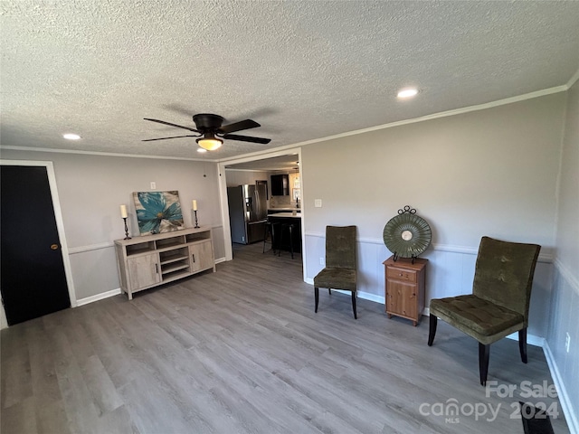 living area with hardwood / wood-style floors, ceiling fan, crown molding, and a textured ceiling