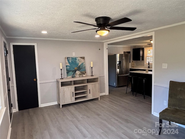 interior space featuring ceiling fan, sink, a textured ceiling, hardwood / wood-style flooring, and ornamental molding