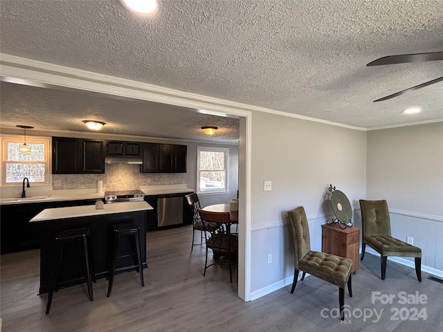 kitchen featuring sink, dark hardwood / wood-style floors, pendant lighting, a textured ceiling, and a breakfast bar area