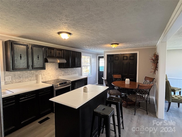 kitchen with a breakfast bar area, a center island, light hardwood / wood-style floors, and stainless steel electric range