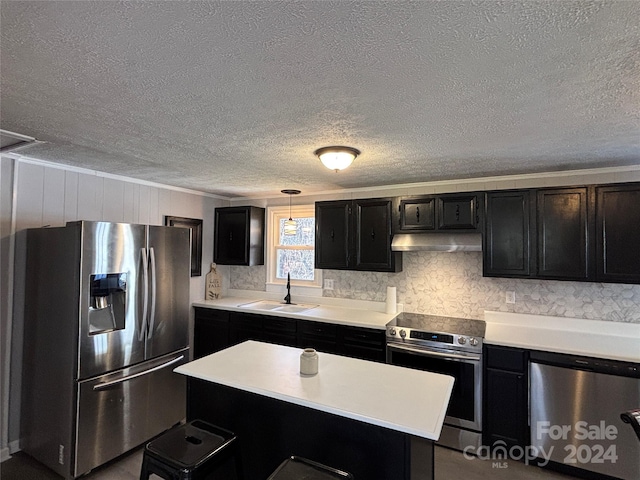 kitchen with a textured ceiling, stainless steel appliances, sink, a center island, and hanging light fixtures