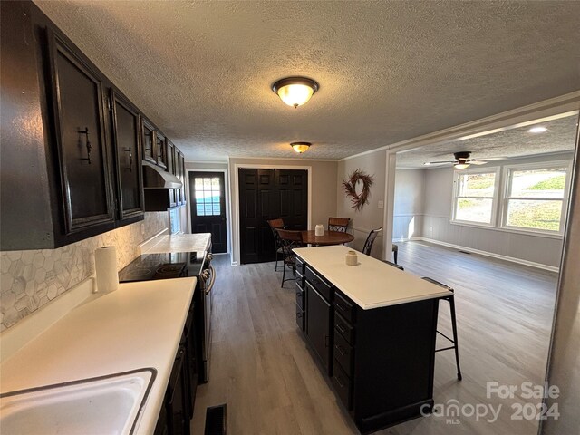 kitchen featuring plenty of natural light, a center island, a textured ceiling, and light hardwood / wood-style flooring