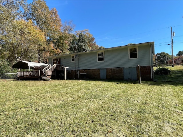 back of property featuring a wooden deck and a lawn