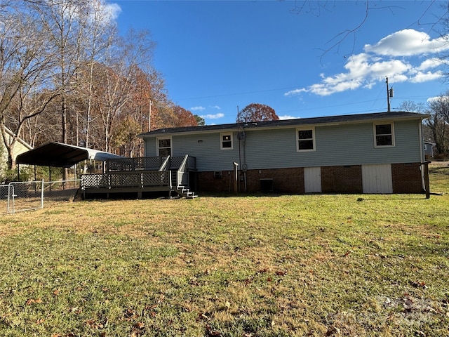 rear view of property with a carport, a wooden deck, and a lawn