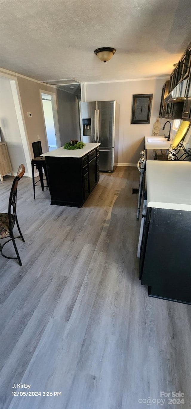 kitchen featuring a textured ceiling, a kitchen island, stainless steel refrigerator with ice dispenser, and light wood-type flooring