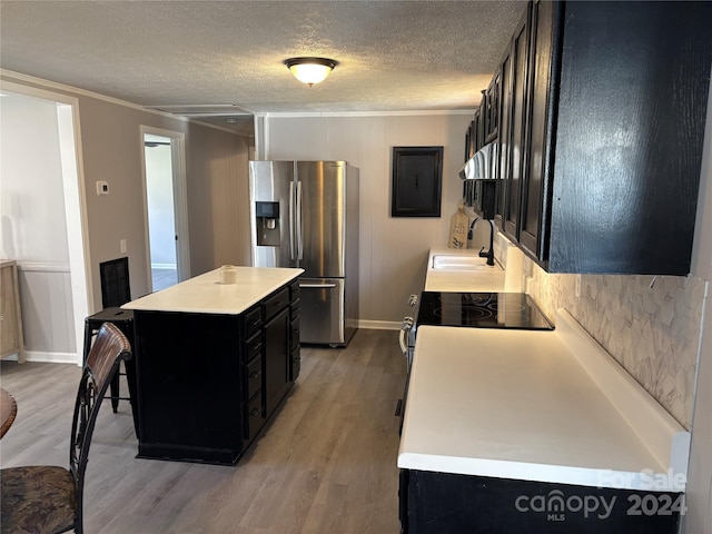 kitchen with crown molding, sink, stainless steel refrigerator with ice dispenser, light wood-type flooring, and a kitchen island