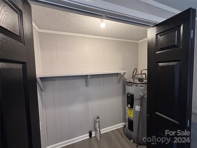 laundry area with wooden walls, electric water heater, dark hardwood / wood-style floors, and ornamental molding