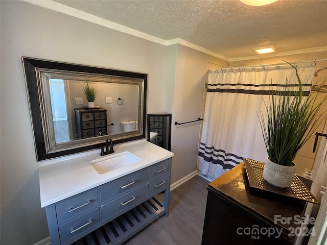 bathroom featuring hardwood / wood-style floors, vanity, toilet, ornamental molding, and a textured ceiling