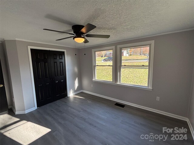 unfurnished bedroom featuring dark hardwood / wood-style flooring, a textured ceiling, ceiling fan, crown molding, and a closet